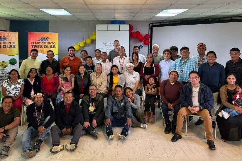 A diverse group of people, including many Indigenous individuals, smiling and posing for a group photo indoors at a workshop.