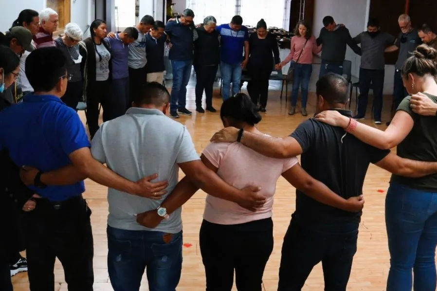 A group of people standing arm in arm in a circle.