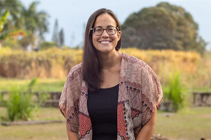A young adult woman with long brown hair and glasses.