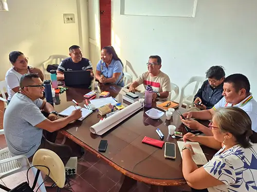 A group of Indigenous men and women sit around a large conference table during a strategic planning session.